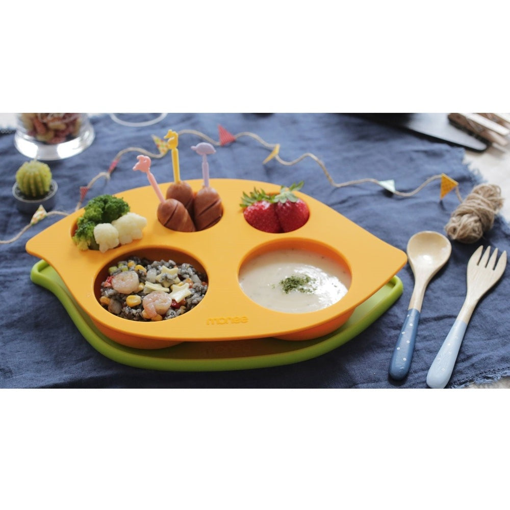 Monee Kids Food Plate Combo orange multi-section plate on a green base, filled with assorted veggies, fruit, and soup.