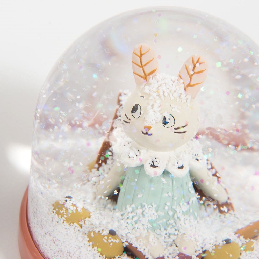Moulin Roty snow globe with a white bunny in a pale blue dress among glittery snow