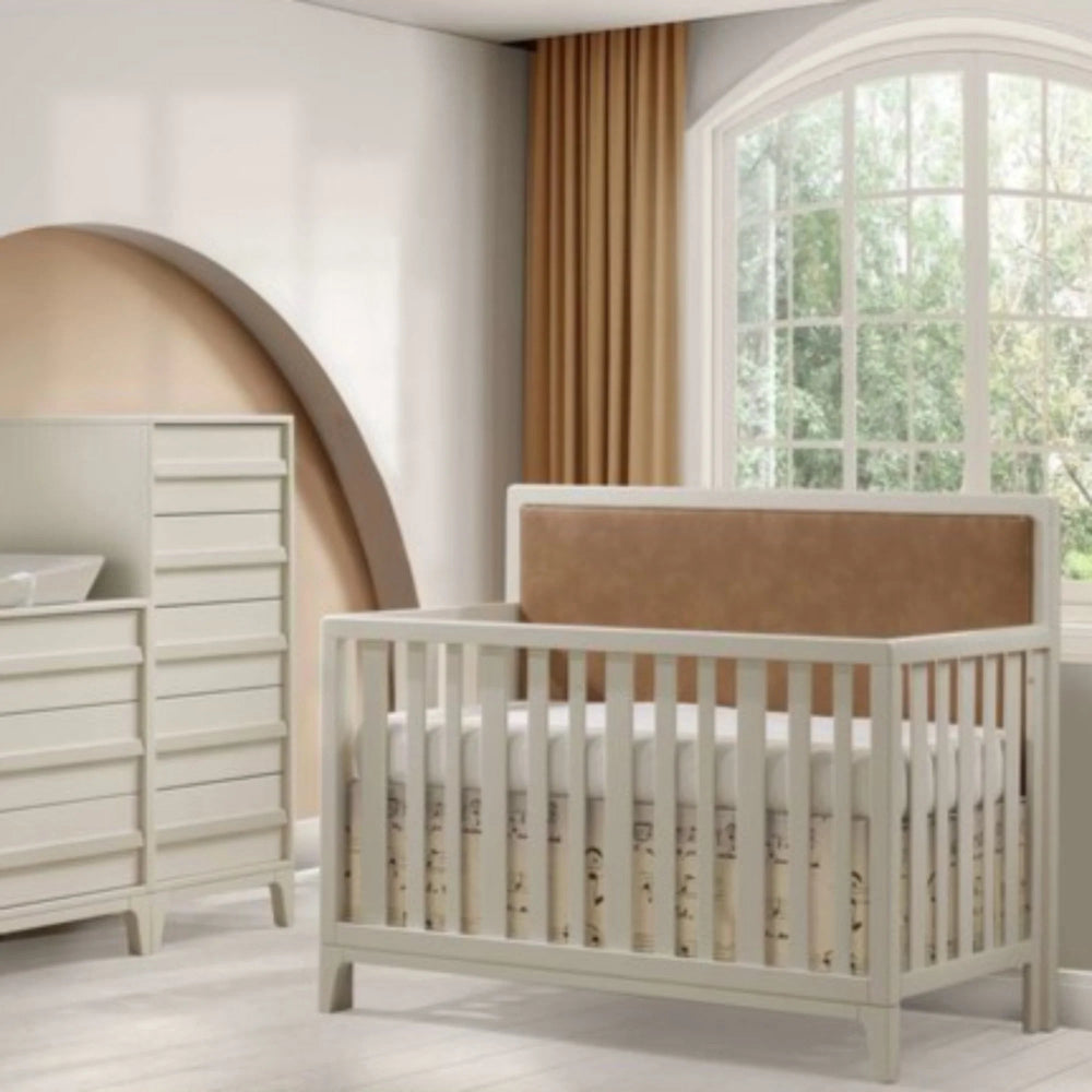 Natart Kyoto 5-in-1 convertible crib with leather upholstered panel and white frame in a bright nursery.