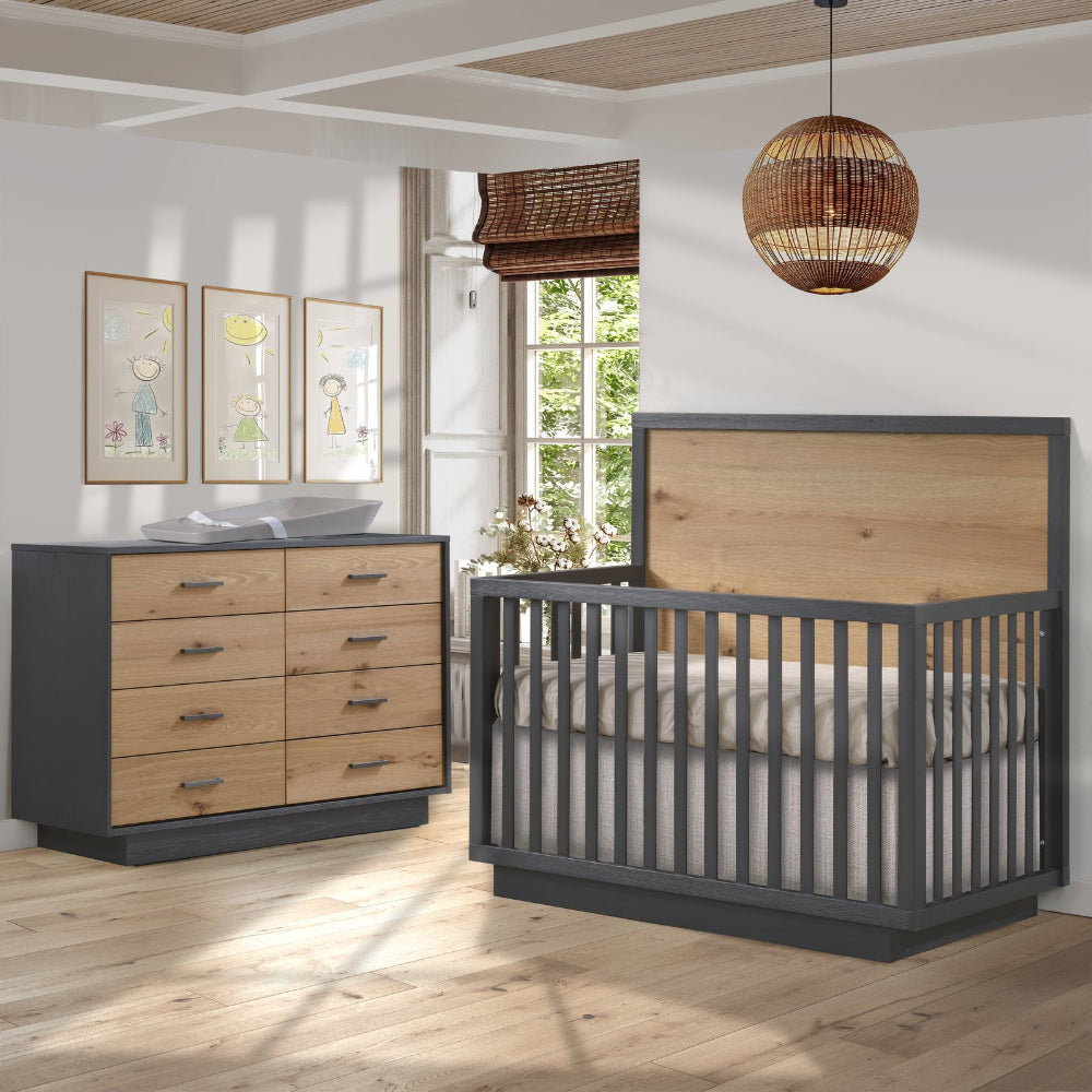 Natart Signature Series Como Naturale Nightstand in a dark frame with natural wood drawers beside a crib in a sunlit nursery.