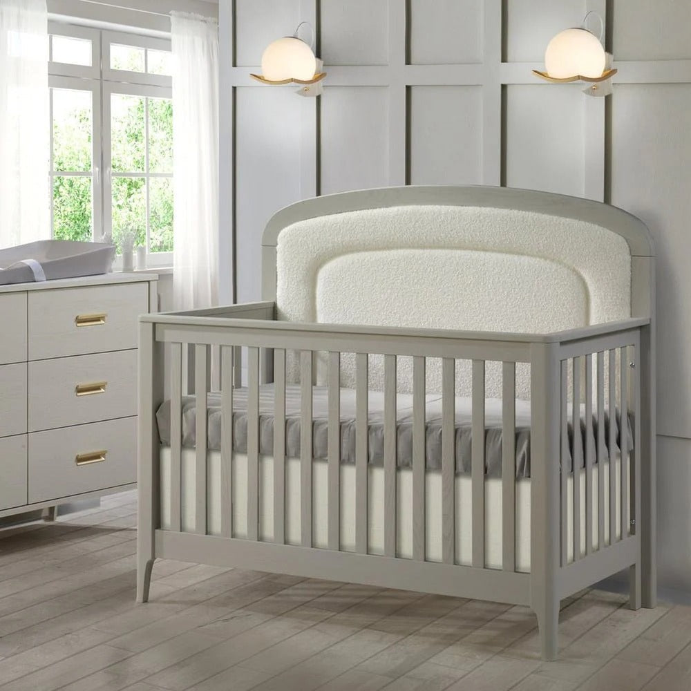 Natart Palo 5-in-1 convertible crib with gray upholstered panel and slatted sides