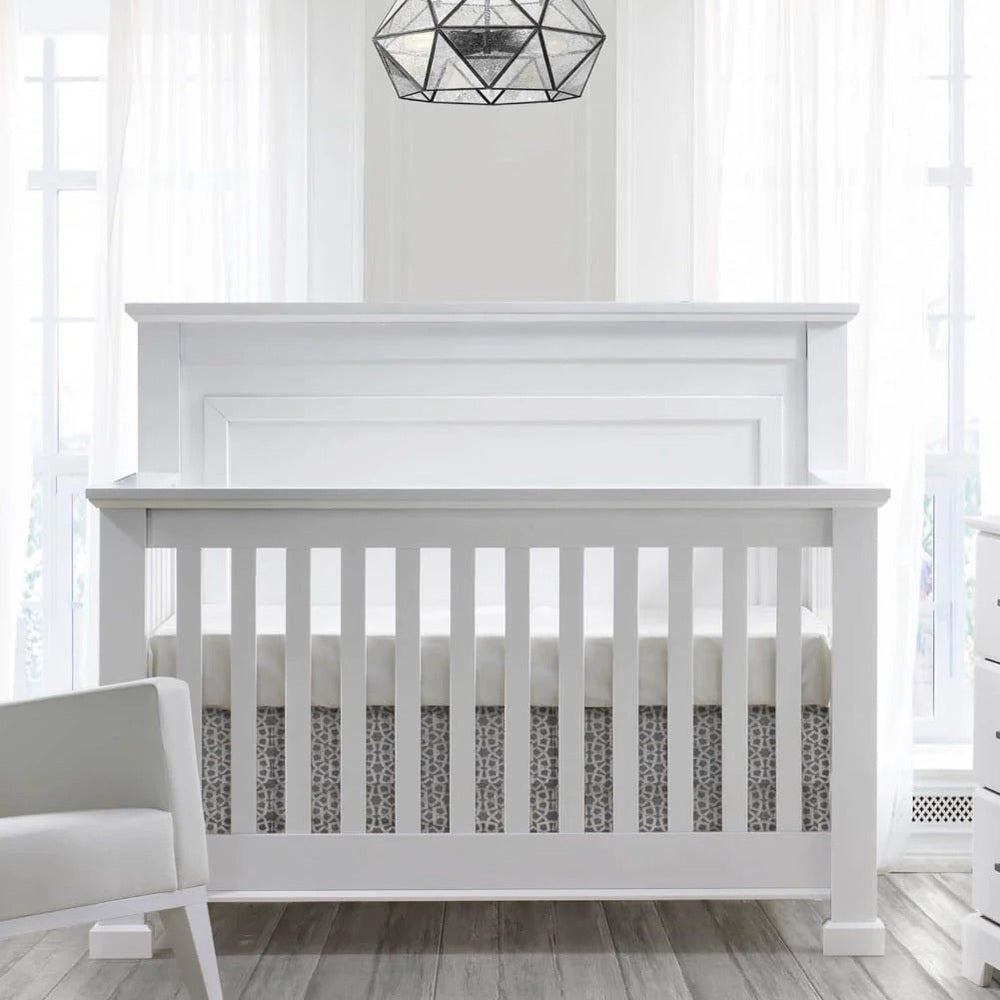 Natart Taylor 5-in-1 convertible crib in white with slatted rails and paneled headboard in a sunlit nursery