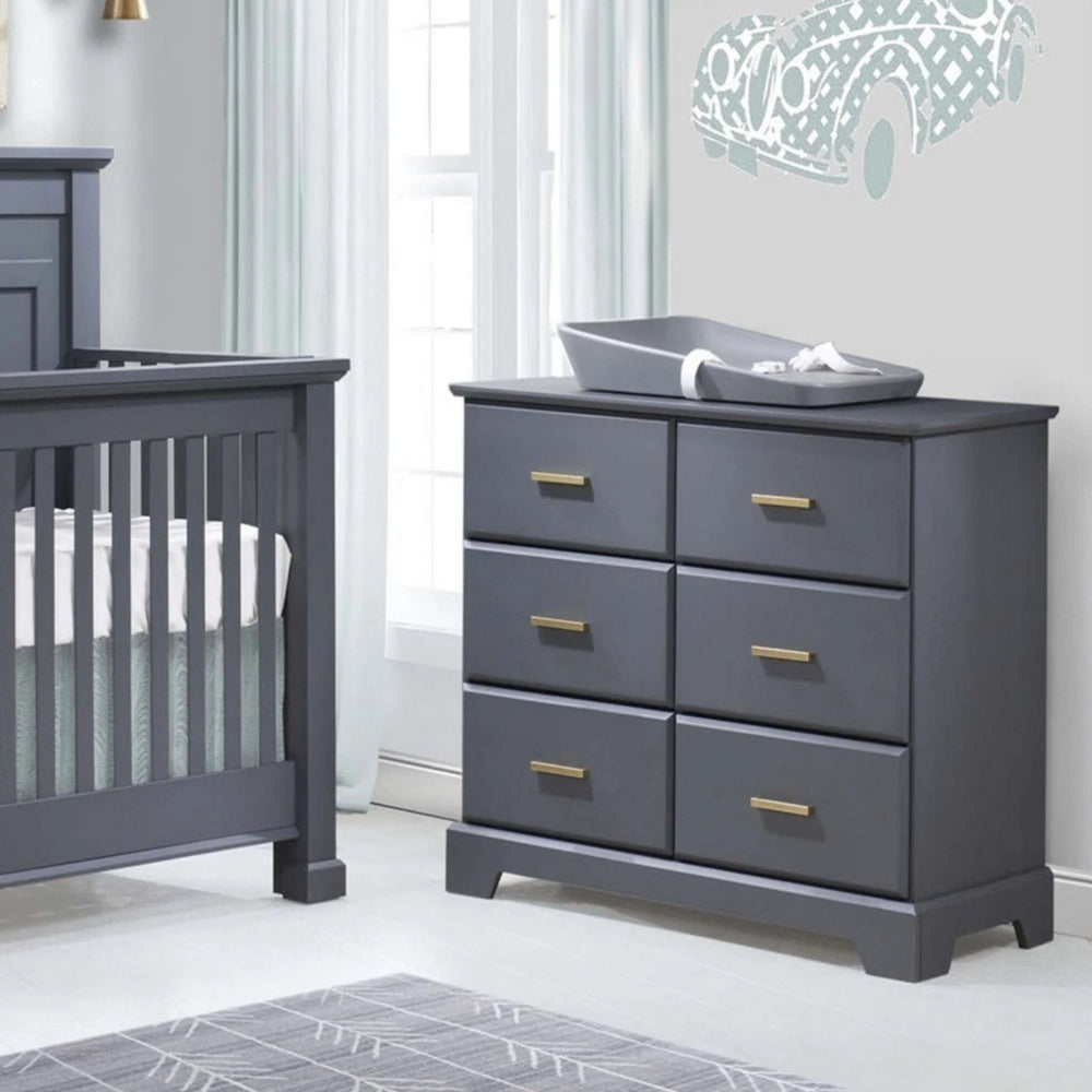 Natart Taylor King Dresser in gray finish with brass handles, six drawers shown beside a gray crib.