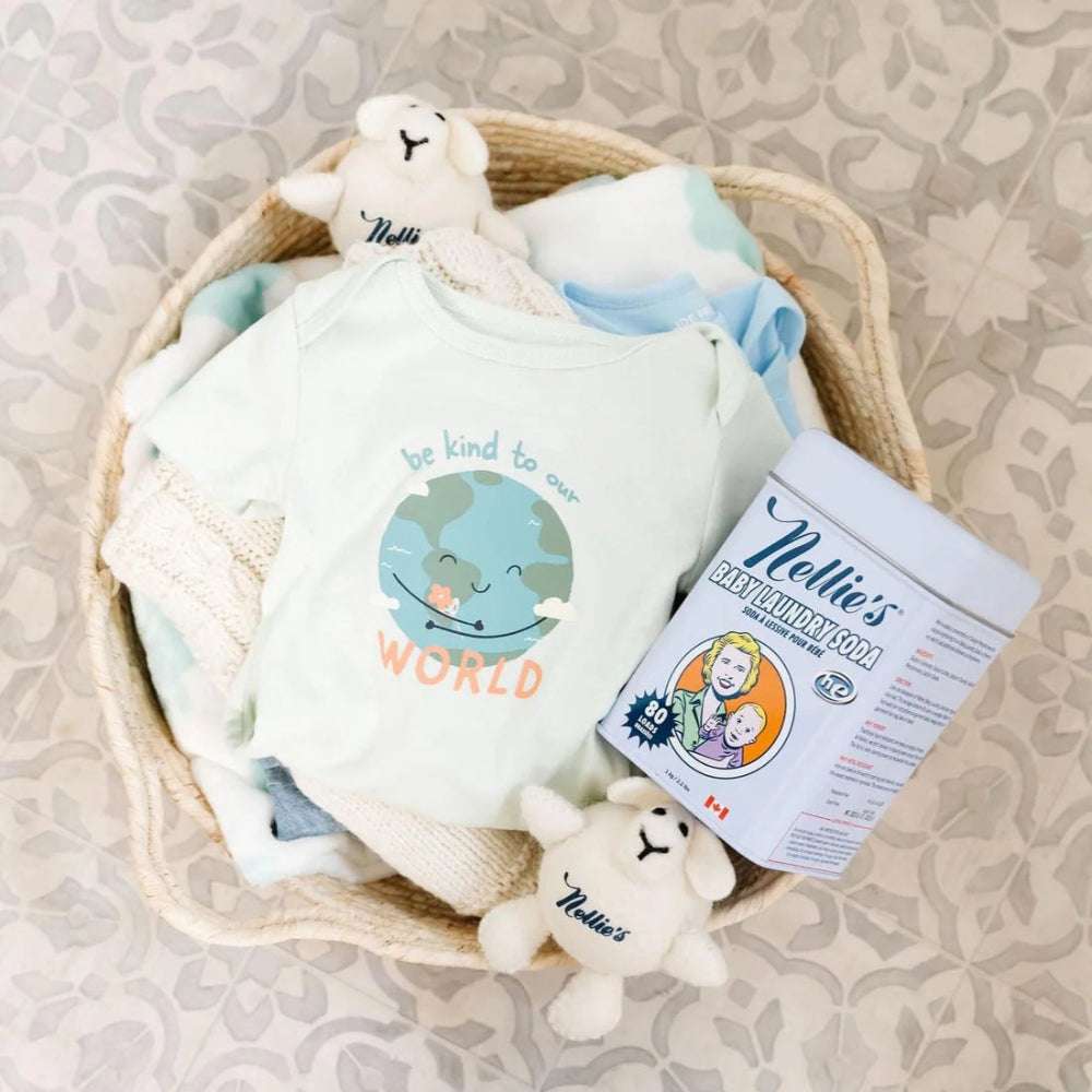 Nellie's Baby Laundry Soda tin with pastel baby clothes and plush toys in a woven basket