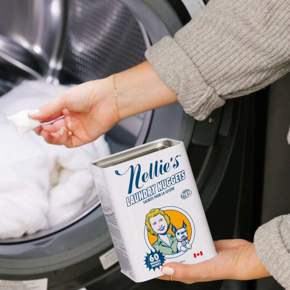 Nellie's Laundry Nuggets box with 60 sachets, held beside a front-loading washer.
