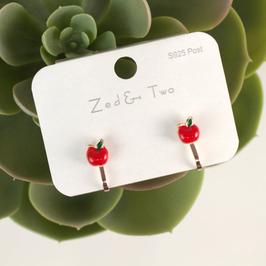 Nemibaby earrings: red apple stud pair with green leaves on white display card.