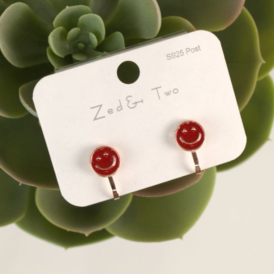 Nemibaby Smile earrings: red smiley studs with silver posts worn on a display card