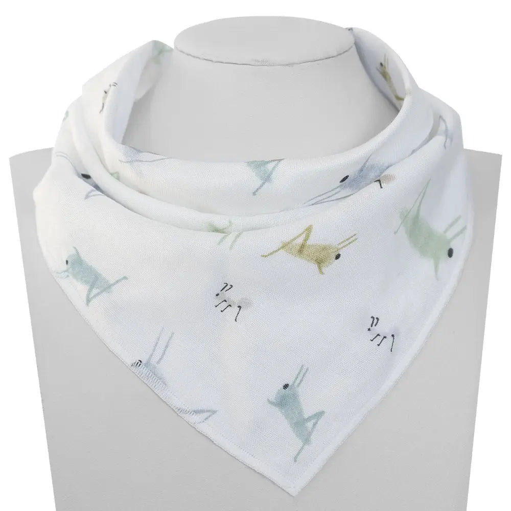 Nest Designs Bamboo Baby Bandana Bib One Size (3M-24M) worn around a baby's neck; white fabric with pastel animal prints.