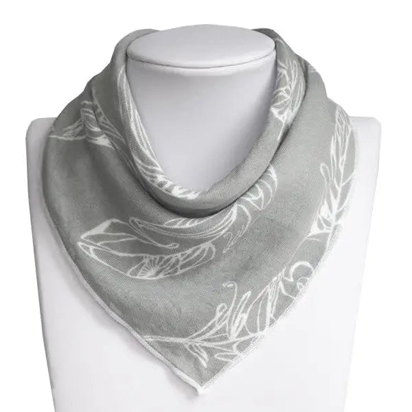 Nest Designs Bamboo Baby Bandana Bib, gray with white leaf print, displayed on a bust to show one-size 3M-24M.