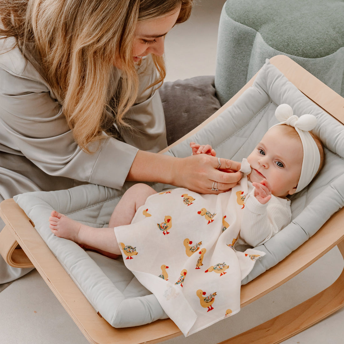 Parent wiping a baby cheek with a cream Flights Of Fancy duck-print washcloth.