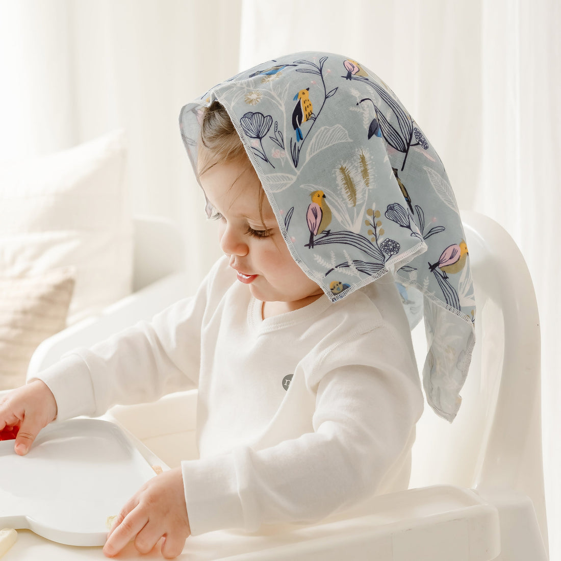 Child wearing a light blue Flights Of Fancy bird-print washcloth draped over the head.