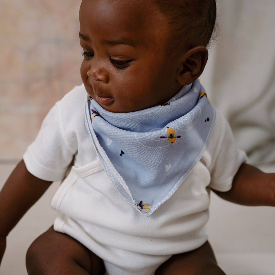 Child holding a small object while a white Buses And Boats bus-print washcloth covers the head.