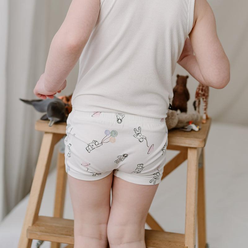 Nest Designs Bamboo Girls Boy Short Underwear 2-Pack To Infinity: child in white tank top wears white shorts with astronaut/balloon print.