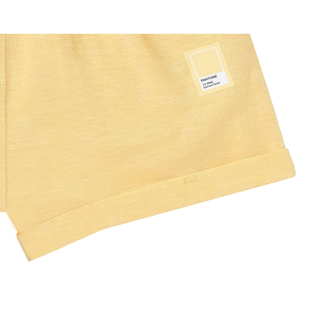 Nest Designs Bamboo Jersey Shorts Pantone Sunset Gold; soft fabric drapes with rolled cuffs and Pantone label visible.