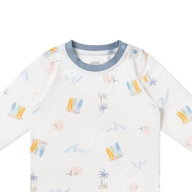 Nest Designs Bamboo Jersey Two-Piece Long Sleeve Pajama Set in pastel waves, blue neckband with shoulder snaps on a baby.