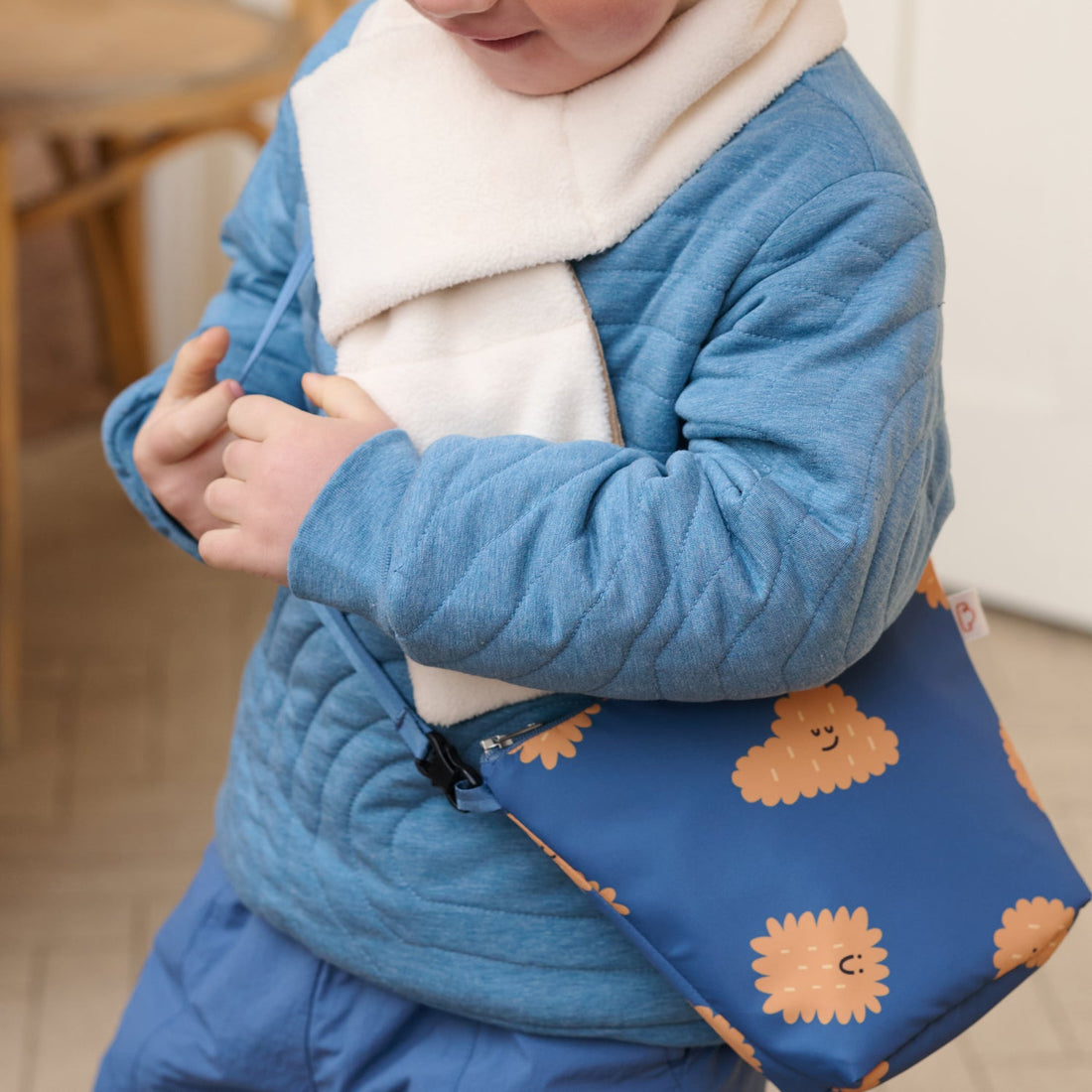 Nest Designs Biscuits and Vine waterproof bag in Biscuit Banter navy worn across a blue quilted outfit beneath a cream scarf