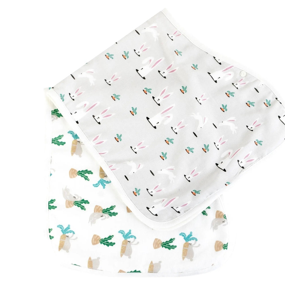 Nest Designs Burp'N Bib 2-pack of white bibs with bunny and carrot print; top bib folded back to show print.