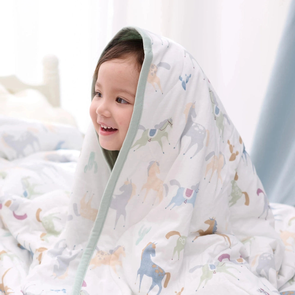 Nest Designs Bamboo Jersey Nook Quilted Cozy Blanket Small Pony Express in White with pastel horse print and mint trim