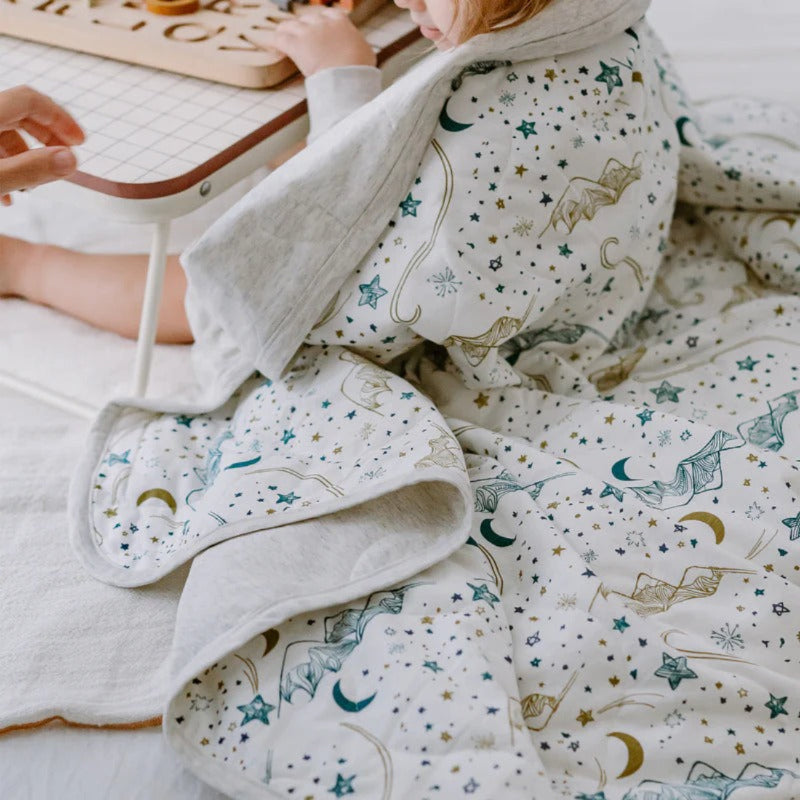 Nest Designs Cozy Blanket Small Stars White wrapped around a child, showcasing its soft, star-patterned comfort.