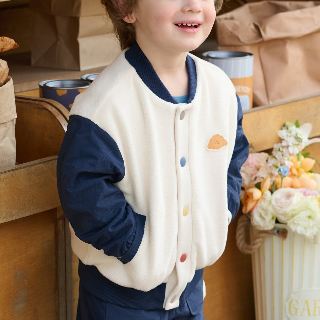 Nest Designs Blueberry Cozy Croissant Fleece Jacket worn with hands in the pockets, highlighting the cream fleece body and navy sleeves