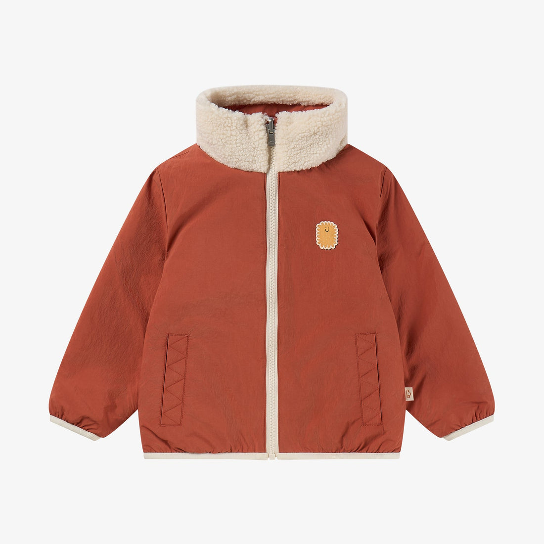 Nest Designs Cozy Crumbs reversible jacket in Redwood Burl rust, nylon-side front with cream fleece collar and biscuit patch