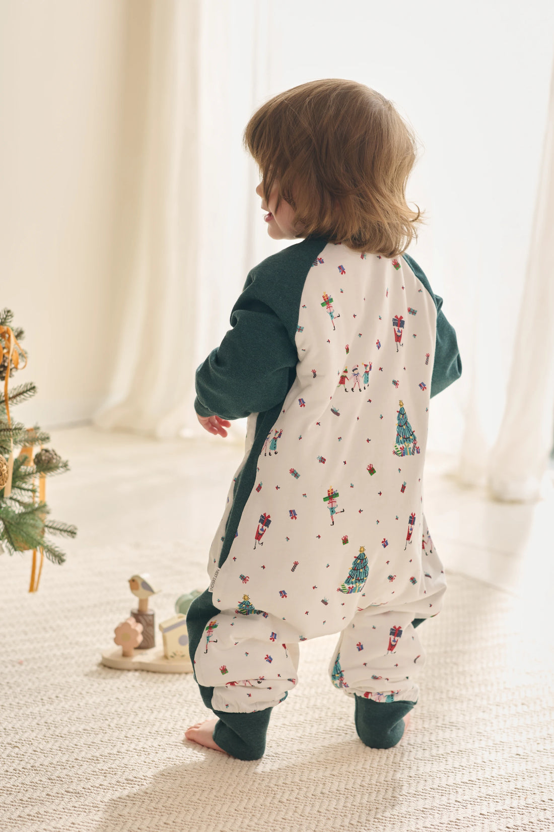 Nest Designs Santas Elves: full back view of the green-sleeve sleep bag worn by a child