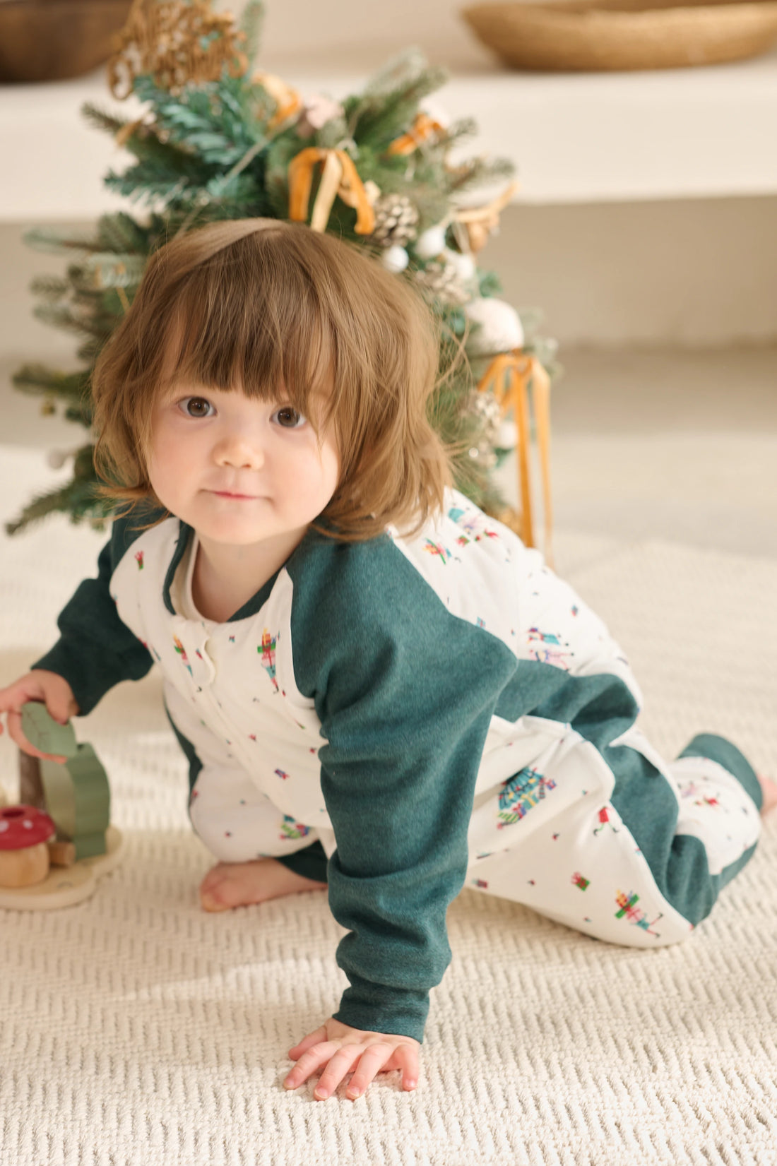 Nest Designs Santas Elves: child kneeling in the green-sleeve sleep bag during indoor play