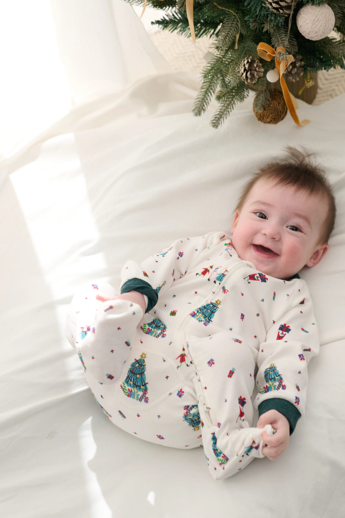 Nest Designs Santas Elves: awake baby wearing the footed sleeper on white bedding