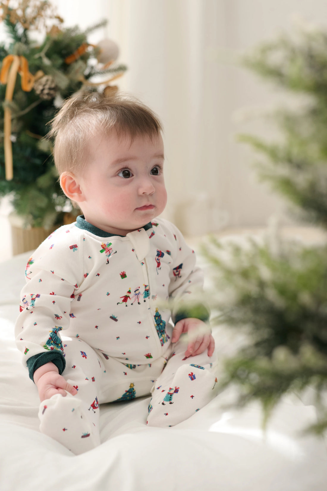 Nest Designs Santas Elves: seated baby showing the side and enclosed feet of the footed sleeper