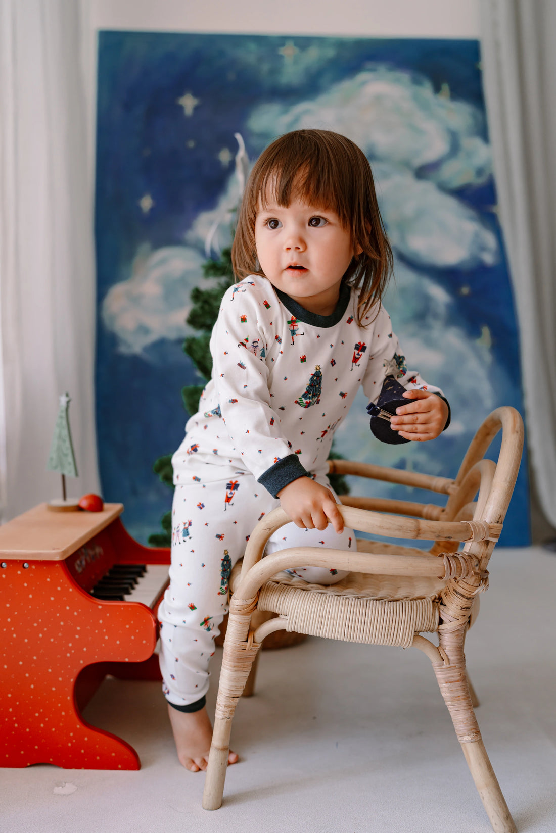 Nest Designs Santas Elves: child seated on a chair in the matching pajama top and pants