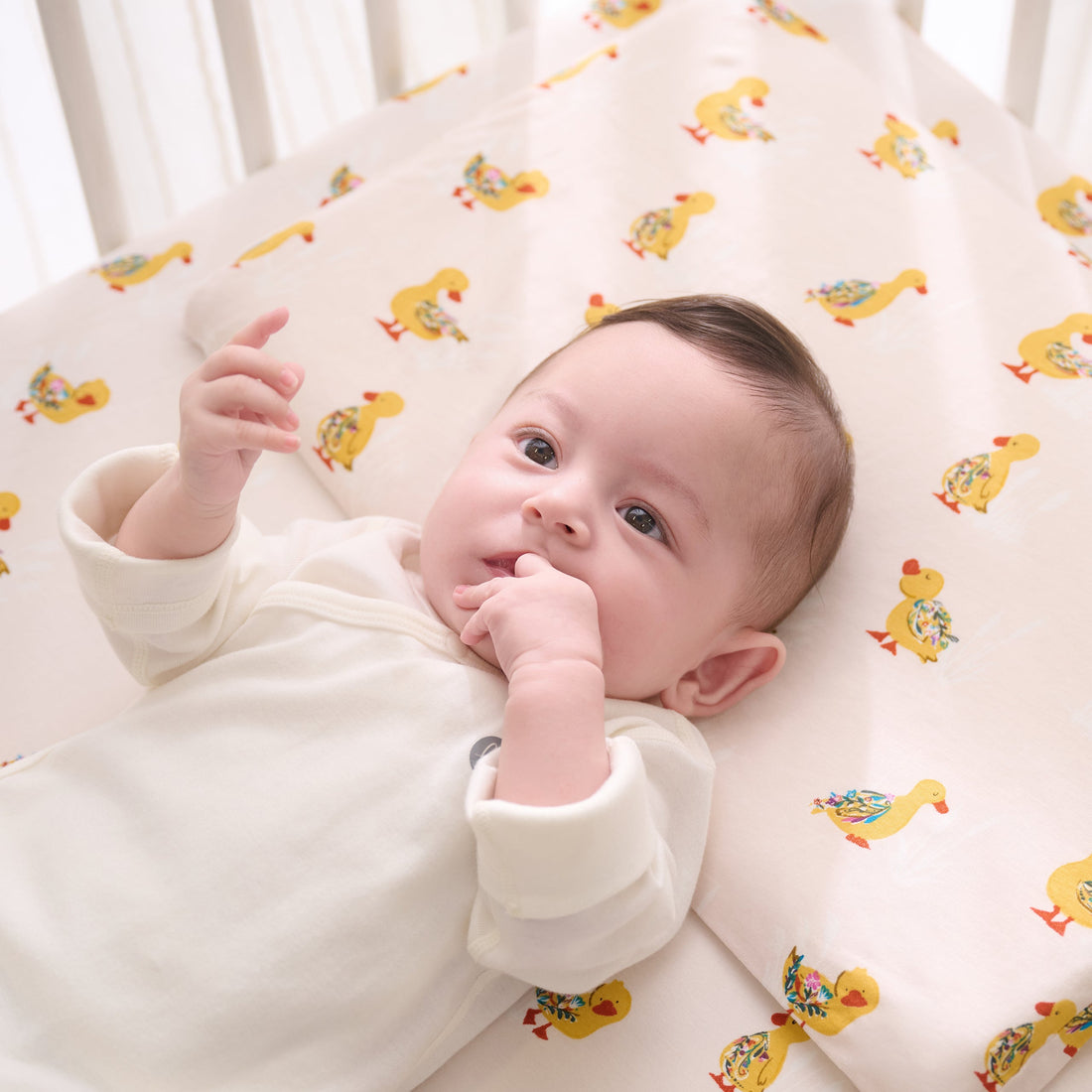 Baby lying on the Five Little Ducks pillowcase in a crib