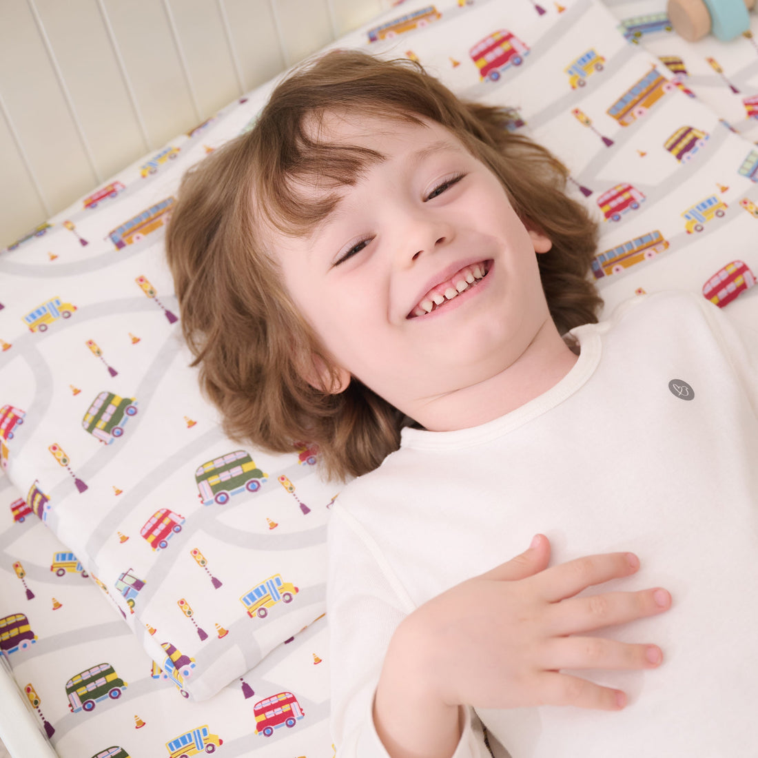 Smiling toddler resting on the Wheels on the Bus Nook pillow