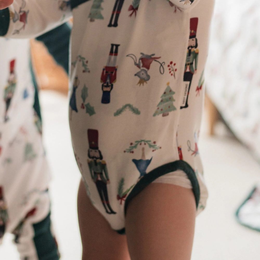Nest Designs Organic Cotton Long Sleeve Kimono Onesie Nutcracker being worn by a toddler in festive Nutcracker print.