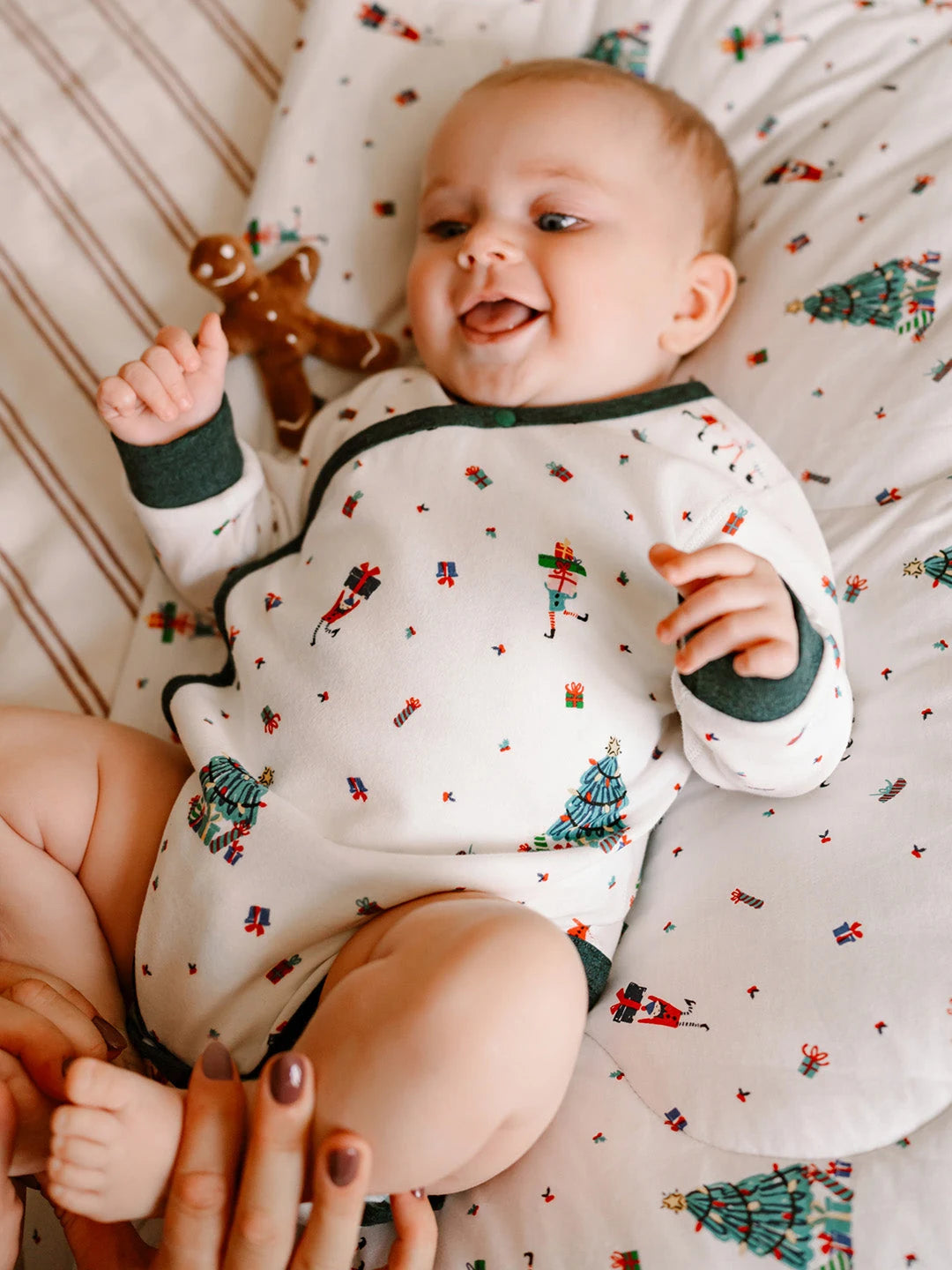 Nest Designs Organic Cotton Long Sleeve Kimono Onesie – Santas Elves, baby lying on a holiday blanket in the kimono onesie