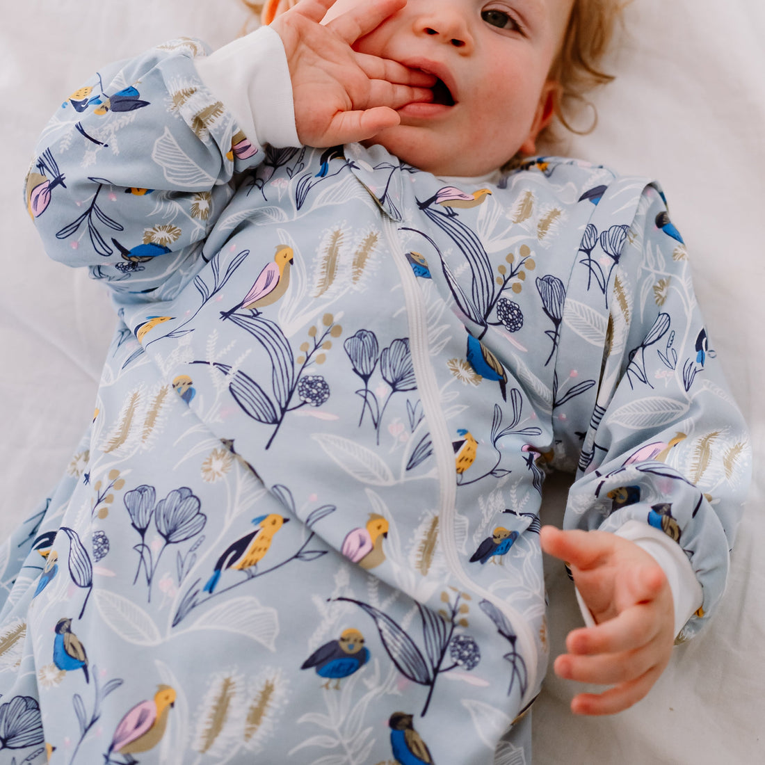 Toddler reclining in the Alouette sleep bag, close view of the bird-and-floral print
