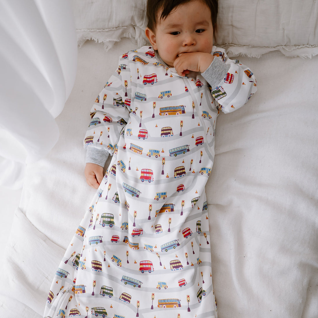 Baby lying full-length on a bed wearing the Wheels On The Bus sleep bag
