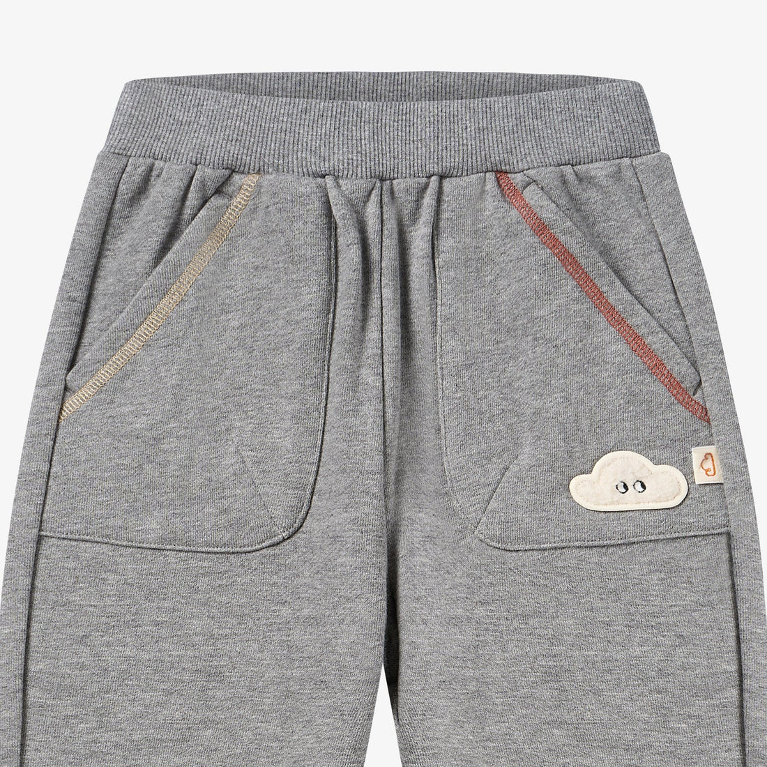 Nest Designs Joggers in Pebble Grey, waist detail with oversized pockets, tan and red piping, and cloud patch