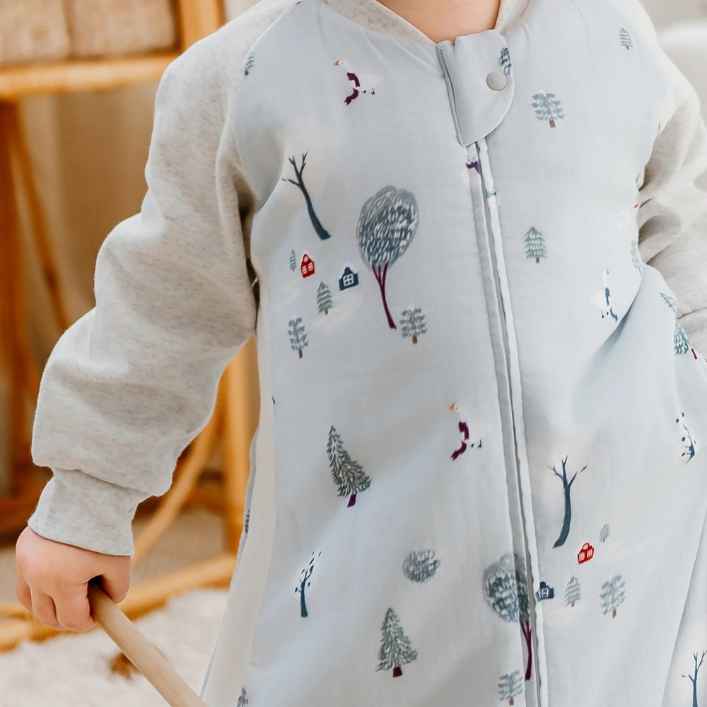 Nest Designs Raglan Bamboo Sleep Bag Snowy Snuggles; baby stands in a