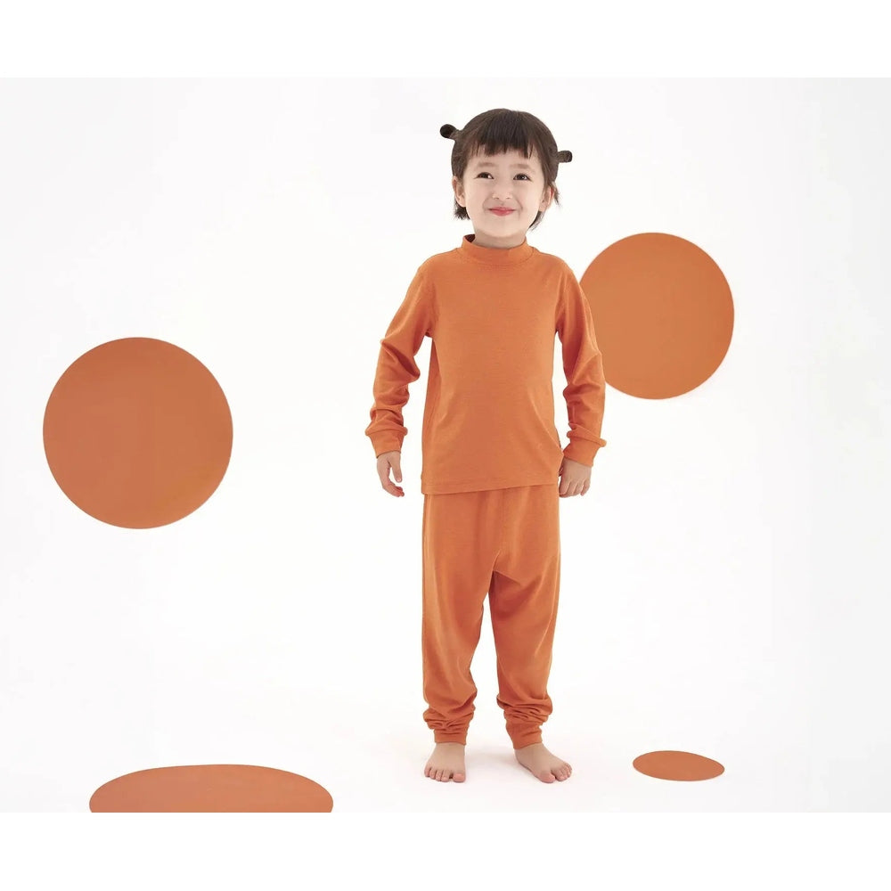 Nest Designs Tanboocel Pants Pantone Apricot Orange worn by a child standing barefoot in a matching orange