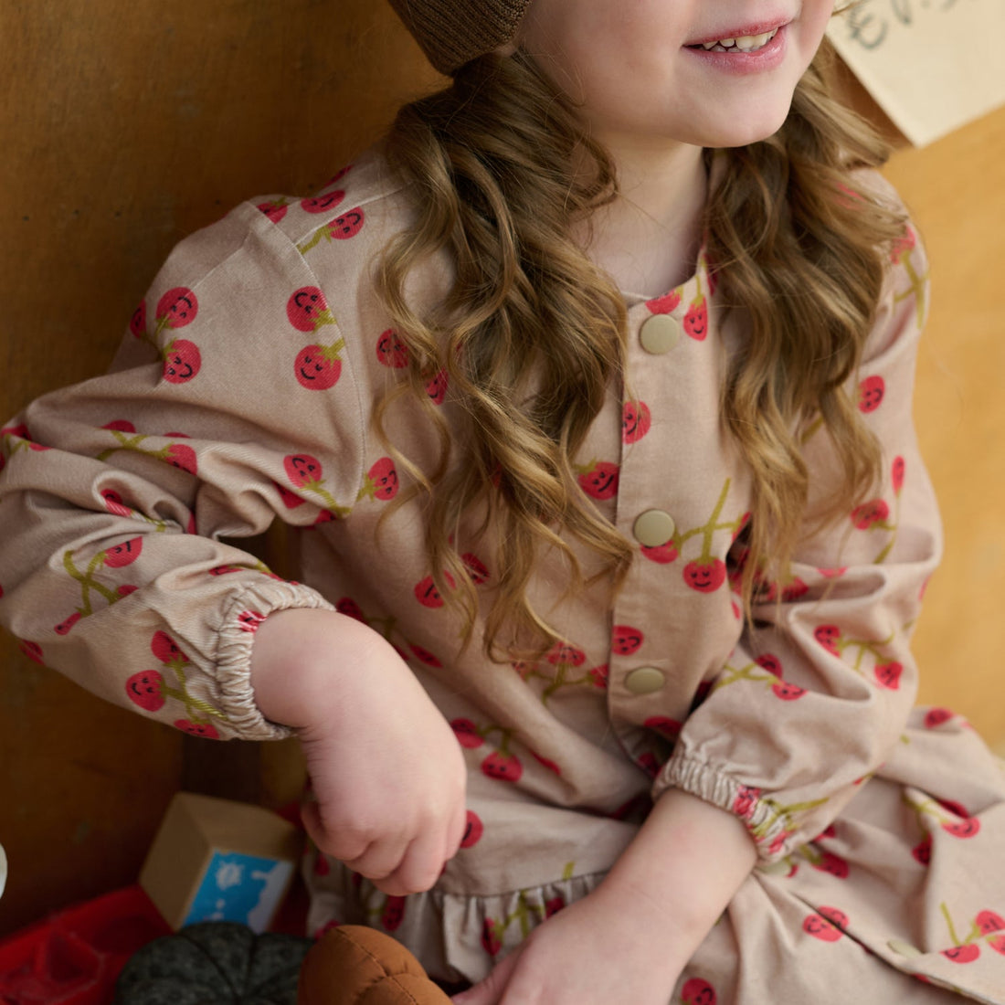 Nest Designs You're So Vine blush corduroy dress, seated close-up of button front, gathered sleeve, and cherry print