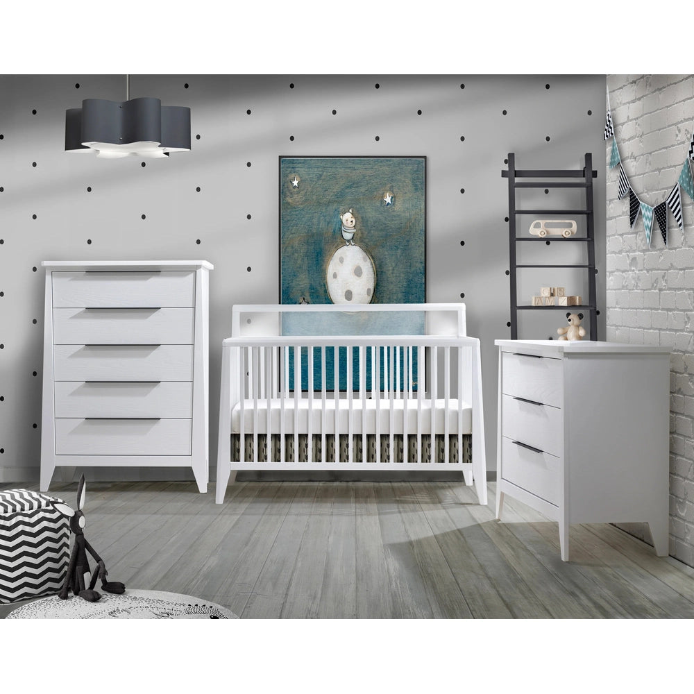 Nest Flexx Premium Convertible Crib in white with tall rails, beside a matching dresser in a gray polka-dot nursery.