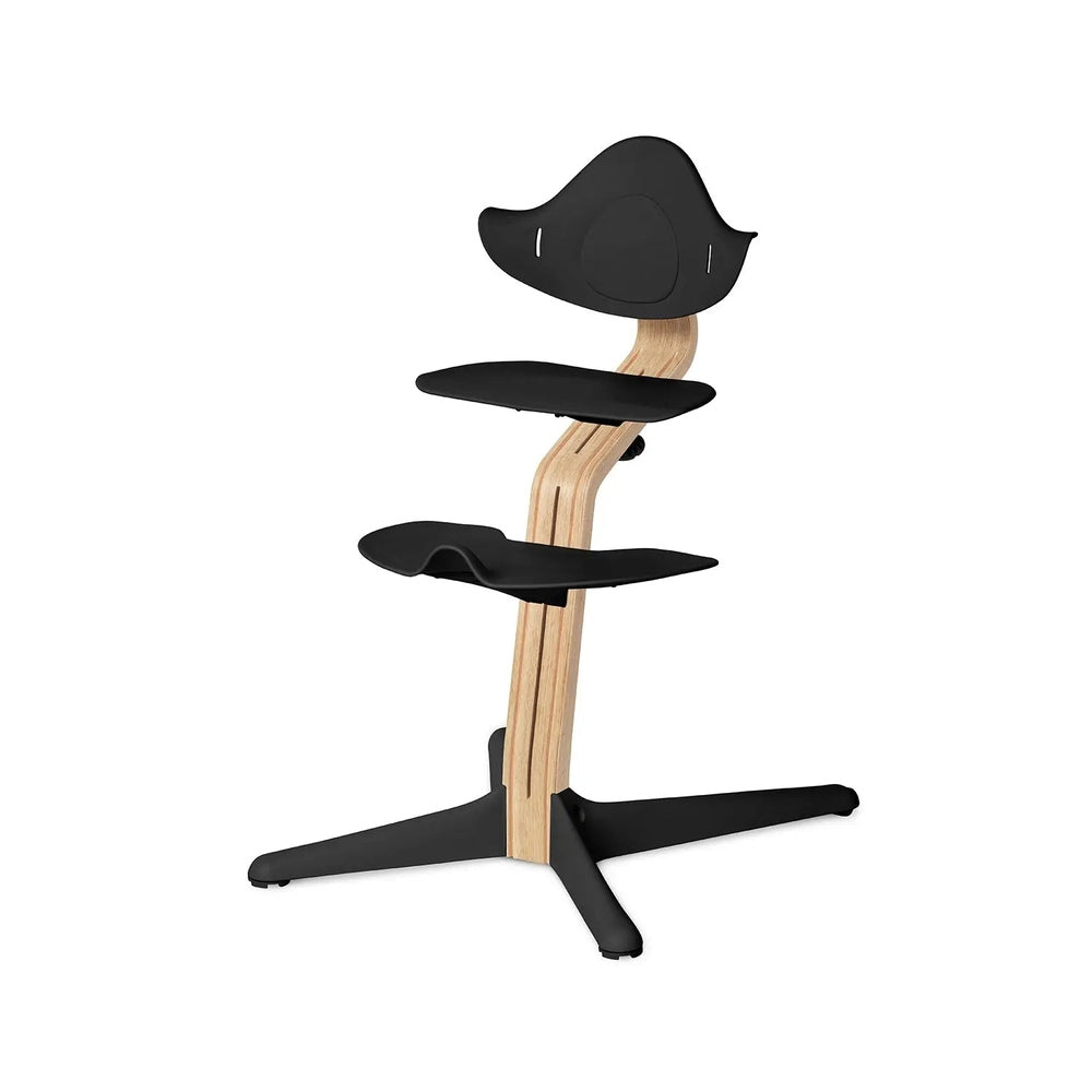 NOMI Chair White Oak high chair with black padded seats and a curved wooden frame for sturdy support.
