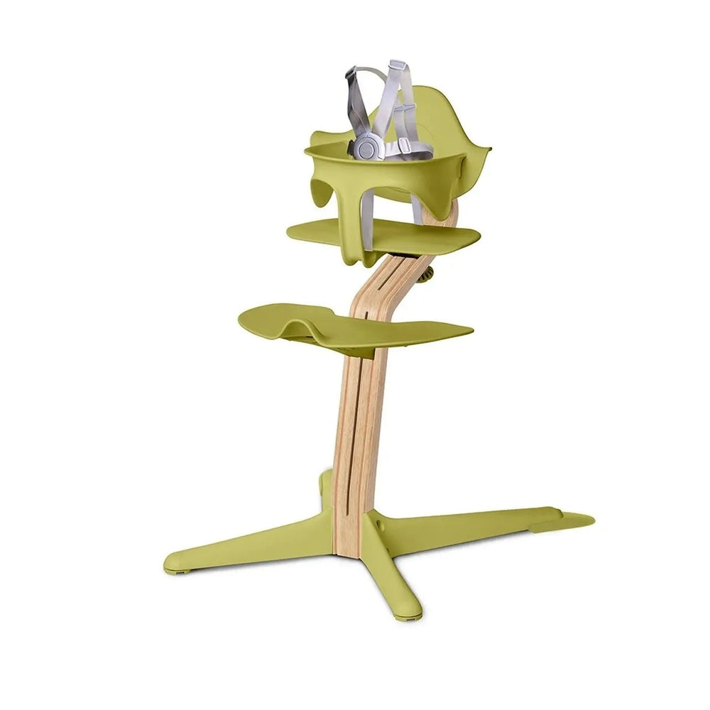 NOMI Highchair White Oak in lime green with natural wood frame; harness fastened to secure baby at mealtime.