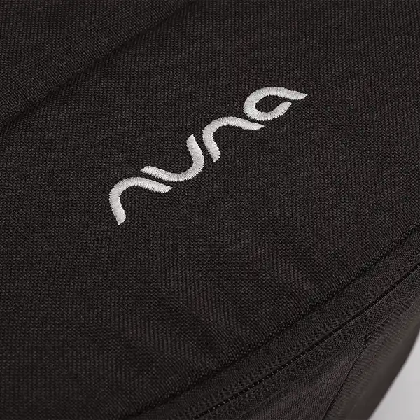 Nuna DEMI next Bassinet — Close-up of embroidered Nuna logo and zipper seam on Caviar fabric