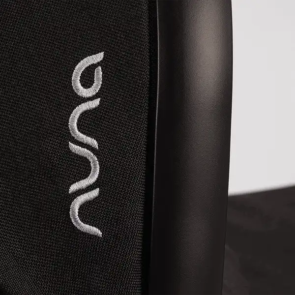 Nuna DEMI next Bassinet — Close-up of Nuna logo beside the DEMI next Bassinet Caviar carry handle