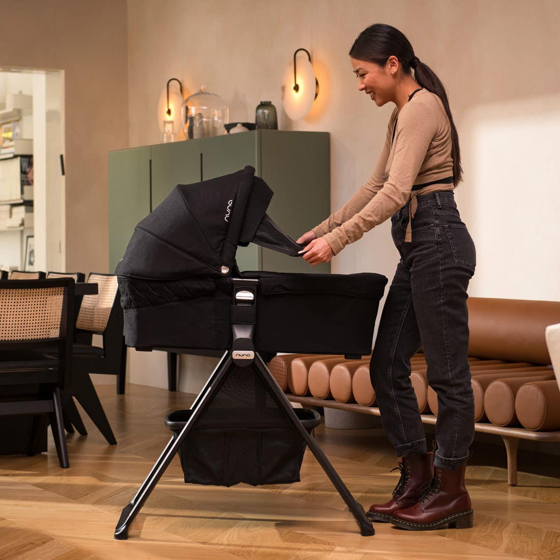 Nuna MIXX Series Bassinet — woman adjusting black bassinet canopy on stand