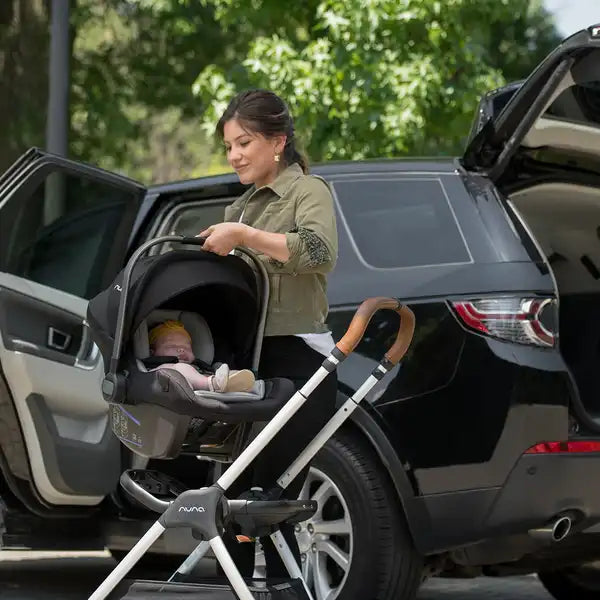 Nuna PIPA lite Infant Car Seat in Caviar - being attached to a Nuna stroller beside a vehicle