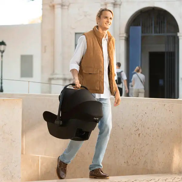 Nuna PIPA lite Infant Car Seat in Caviar - carried outdoors by a parent