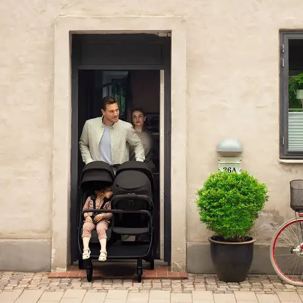 Nuna TRVL-DUBL — Family with the double stroller at a doorway