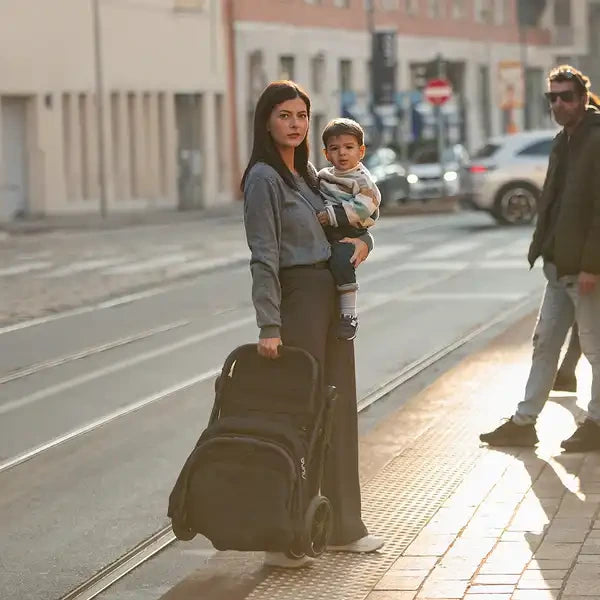 Nuna TRVL-LX — Parent carrying the folded stroller